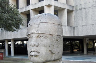 the olmec head statue in front of a building on campus