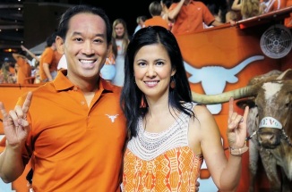 andrew vo stands with wife sophie at a texas game