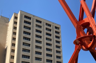 red metal structure next to tall beige building with windows during daytime
