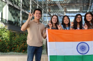 group of students hold up Indian flag near building outside during daytime