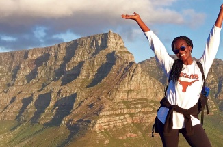 a student poses on a mountain and smiles