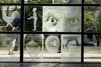 etched glass window wall with various images during daytime near trees
