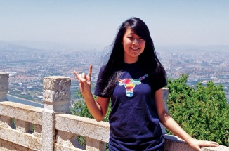 a girl poses in front of a bridge with a UT hand sign 