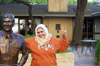 walaa ali smiles and poses with a statue on campus 