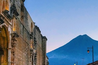 Historic buildings in foreground frame a distant mountaintop in Guatemala