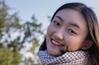 UT alumna SiQi Li smiles in front of Austin's Pennybacker 360 bridge