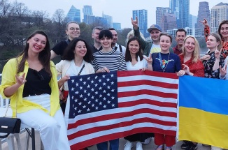 UT's 2023 Ukrainian Business Leaders pose with flags on a boat in front of the Austin skyline