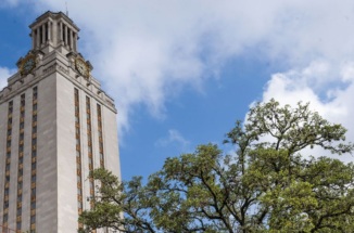 UT Tower with treetop against blue sky with clouds