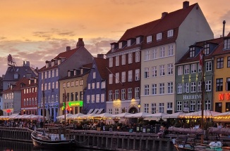 Colorful buildings and boats line the Nyhavn Canal in Copenhagen, Denmark at sunset.