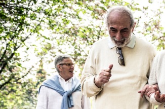 Older Latinx couple walks close together under trees