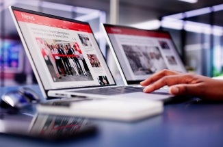 Hand types on a laptop displaying a news site