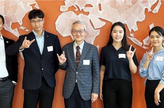 People pose in front of while and hold up "hook em" sign. 