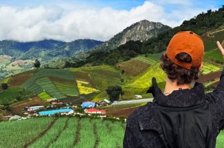 Back of male UT student showing "Hook 'em Horns" to scenic countryside