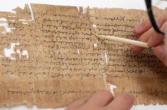 a researcher writes on ancient papyrus paper