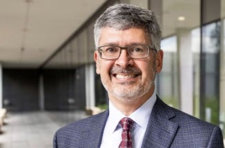 UT Austin Dean of Engineering Roger Bonnecaze smiles in a gray jacket and red tie