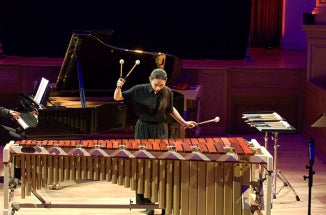 A woman plays a marimba in a music performance hall.