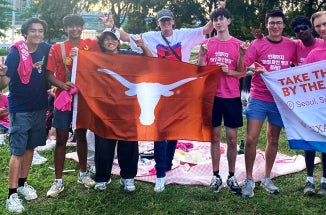 Students with Take the World by the Horns unfurl a Longhorn flag in Seoul