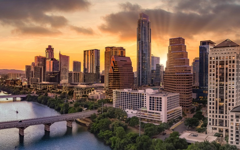 Aerial view of the Austin city skyline from the south side with Lady Bird lake below and a beauitful sunset behind the tall buildings