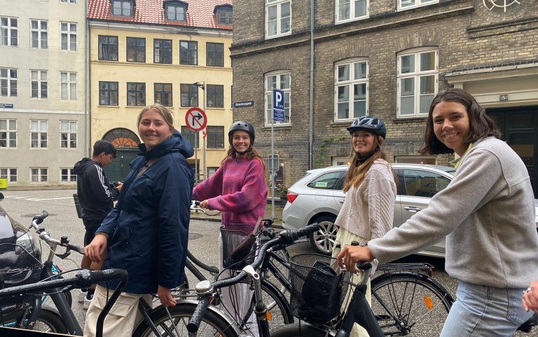 A group of students stop and smile while on bikes in Denmark