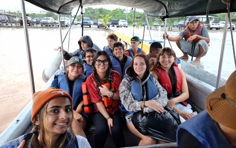 A study abroad group smiles while taking a photo on a boat ride in the rain while studying in Panama