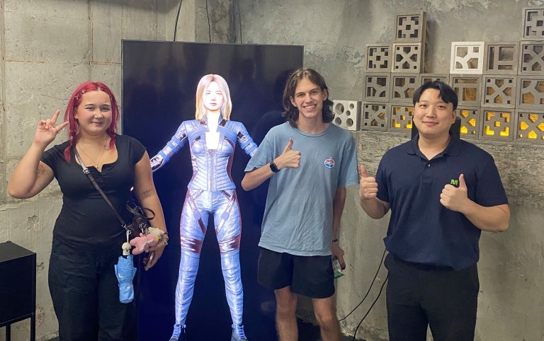 Three smiling students pose in a digital lab in South Korea