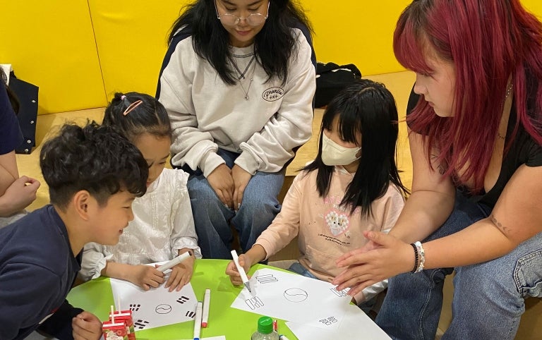 Study abroad students work with children creating art in South Korea