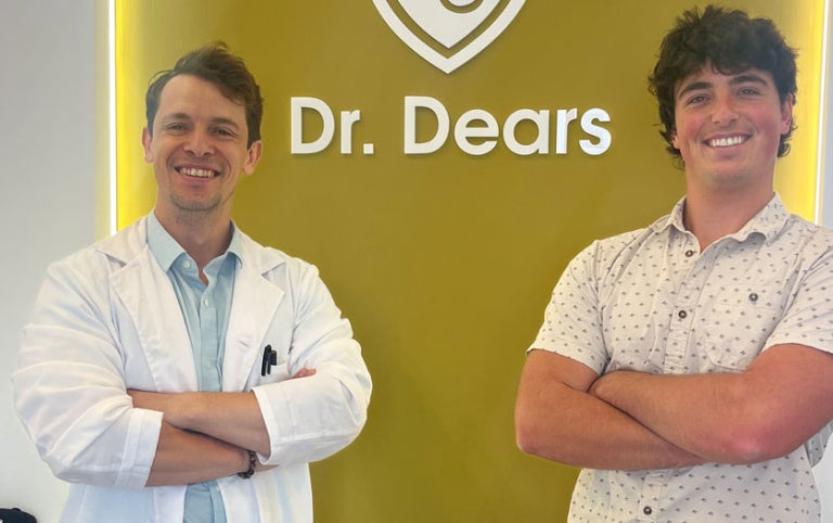 Two male Absolute Internship participants stand in front of sign for Dr. Dears and smile