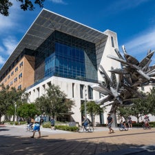 The UT Austin College of Natural Sciences Norman Hackerman Building during the day with the towering canoe art installation out front