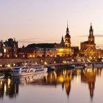 Illuminated buildings and boats during a sunset on the river in Dresden, Germany