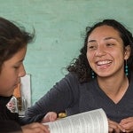 A female peace corps participant works with children in a school