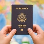A US passport is held up with a map of the world out of focus behind it