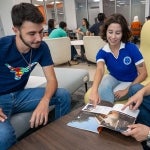 Students in the Texas Global lobby look through a publication