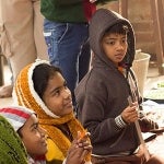 Children in India smile at an instructor holding a book