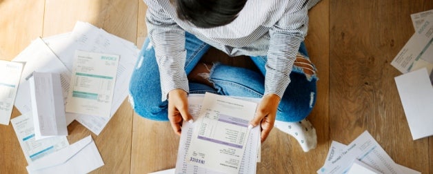 woman sitting on floor surrounded by bills and bank statements