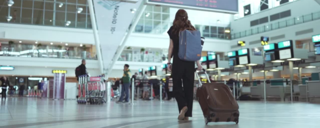 student with suitcase walking through airport