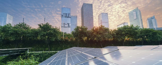 Solar panels backdropped by a city skyline and a beautiful sky