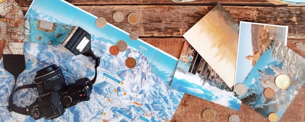 travel imagery, a film camera, and foreign currency scattered over an aged wood table