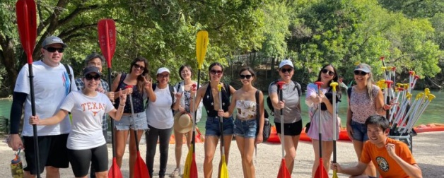 International students smiling and holding kayak oars. 