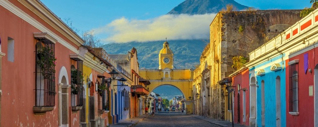 The historic city of Antigua at sunrise with a view over the main street and the Catalina arch and the Agua volcano in the background, Guatemala.