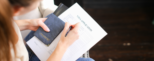 person holding a passport and paper that says visa application on it