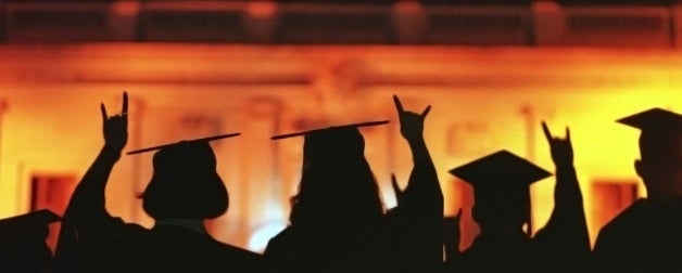 silhouettes of students in graduation caps and gowns on orange and yellow background 
