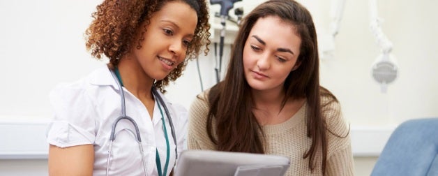  A female doctor looks over the chart of a female student