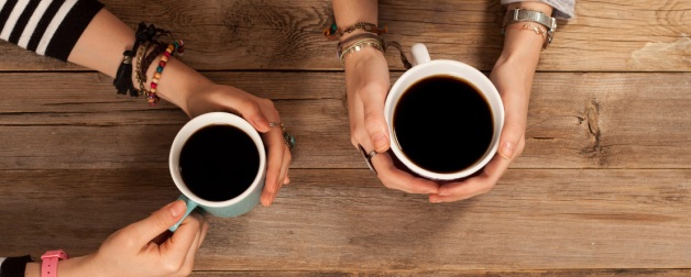 hands around coffee cups on a wooden table