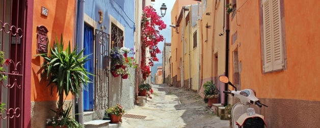 Looking down and a colorful alleyway in Italy, colorful buildings, plants, and a scooter are in view