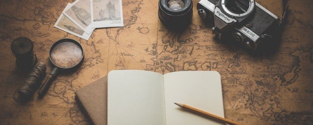 Travel prep - old map with notebook, pencil, film camera, and magnifying glass