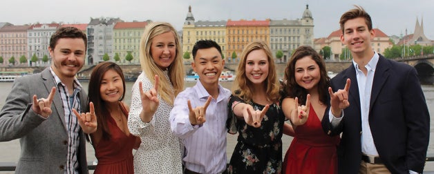 Seven UT students present the "Hook 'em Horns" sign to the camera