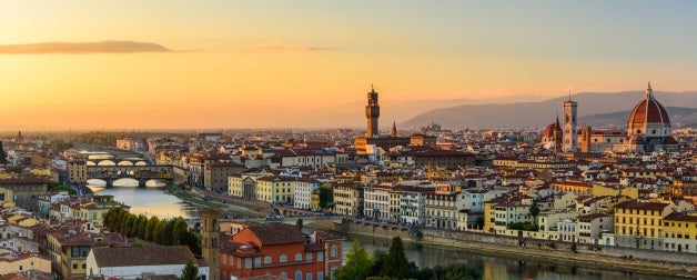 The Florence cityscape with the Ponte Vecchio over Arno river, the Palazzo Vecchio and the Florence Cathedral in an orange sunset.