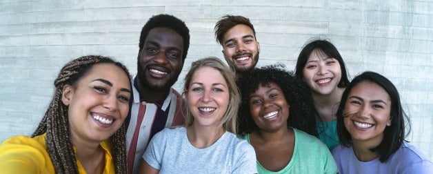 a diverse group of young adults smile for a group photo
