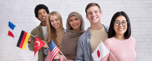 A diverse group of exchange students smiling and holding flags representing different countries