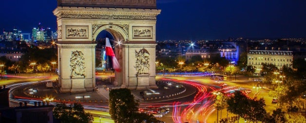 The famous Arc de Triomphe arch illuminated by motorists at night in Paris, France